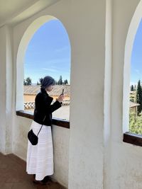 Rear view of young woman standing against historic building