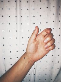 Cropped hand showing tattoo against patterned fabric