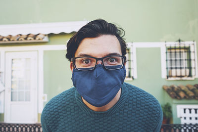 Portrait of young man standing against building