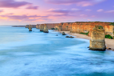 Scenic view of rock formation by sea against cloudy sky