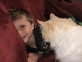 Portrait of boy with cat relaxing on sofa