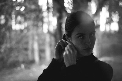 Portrait of young woman wearing earring while standing in forest