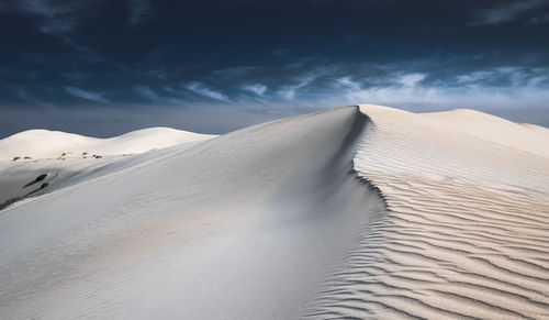 Sand dunes in desert against sky