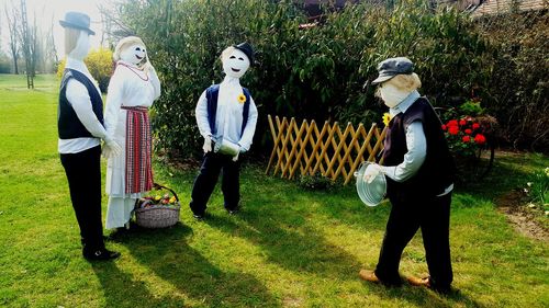 Full length of friends standing on grass during halloween