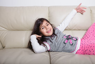 Portrait of happy girl lying on sofa at home