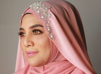 Close-up of woman wearing hijab against gray background