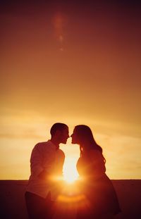 Silhouette couple against orange sky during sunset