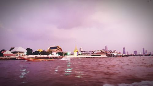 City at waterfront against cloudy sky