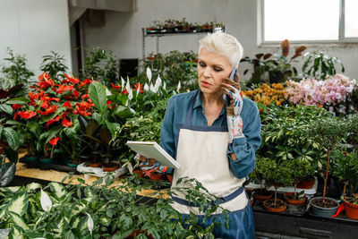 Woman working at plant nursery. smiling woman gardener writing orders