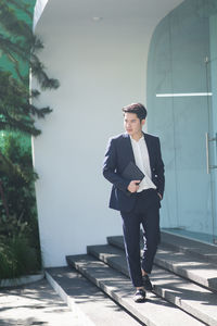 Full length of young man standing against wall