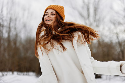 Portrait of young woman standing against trees during winter