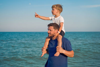 Father carrying son on shoulder at beach