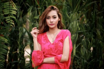 Portrait of young woman standing against plants