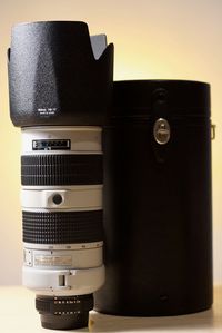 Close-up of camera with container on table against wall