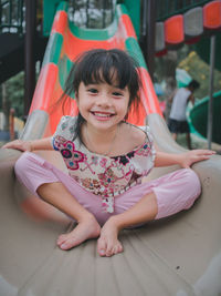 Portrait of cute smiling girl sliding in playground