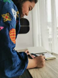 Side view of boy using mobile phone at home