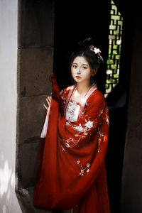 Portrait of young woman standing against wall