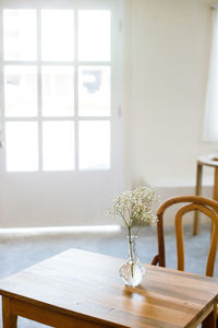 Flower vase on table by window at home