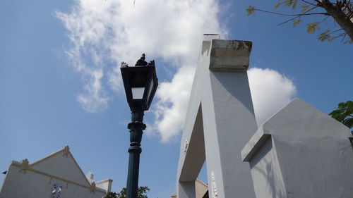 Low angle view of cross amidst buildings against sky