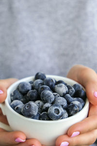 Woman holding bowl with frozen blueberry fruits. harvesting concept. female hands collecting berries