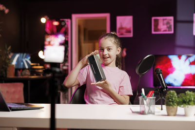 Young woman using mobile phone while sitting on table