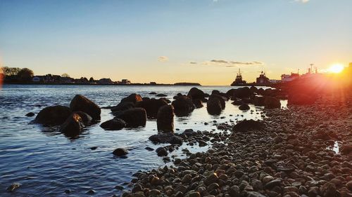 Rocks on beach against sky during sunset