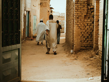 Rear view of people walking in alley in an old neighborhood 