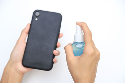Close-up of hand holding smart phone against white background