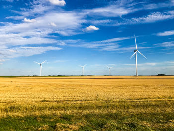 Windmills on field against sky