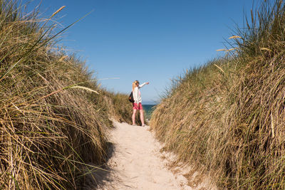 Rear view of woman standing on sand against sea and sky