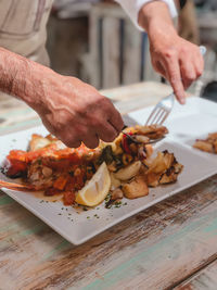 Cropped hands of man eating food on table