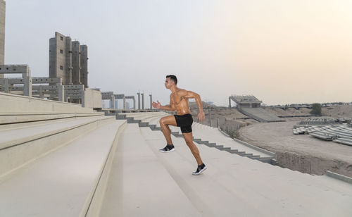 Muscular shirtless man exercising outdoors