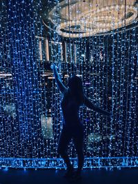 Full length rear view of woman standing at night