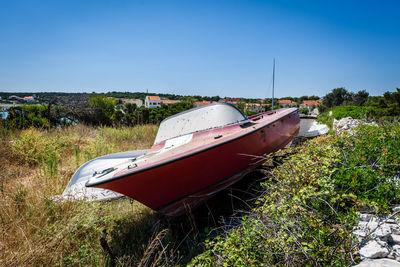 Abandoned boats on field against clear blue sky during sunny day