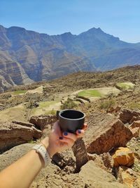 Cropped hand of woman holding coffee on mountain