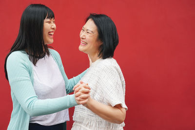 Happy woman standing against red background