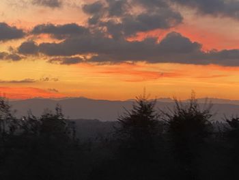 Scenic view of silhouette mountains against orange sky