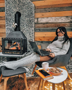 Full length of woman sitting on chair while working on laptop