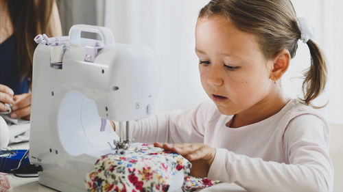 Close-up of cute girl sewing textile at home