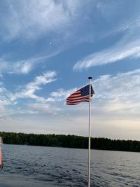 Red flag by river against sky