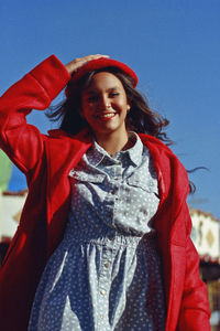 Portrait of smiling teenager girl holding hat while standing in amusement park