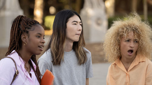 Multi ethnic students looking away with expression of surprise in the face standing on a campus