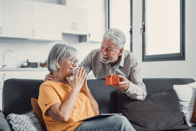 Side view of senior man using mobile phone while sitting at home