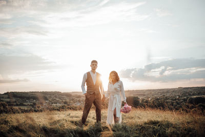 Couple standing on field against sky