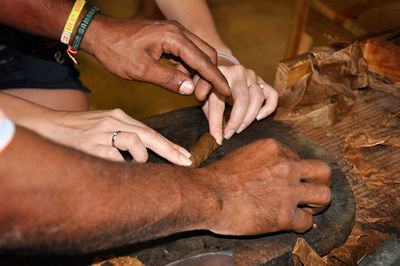 Cropped image of people hands making cigar