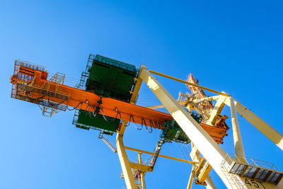 Low angle view of electricity pylon against clear blue sky