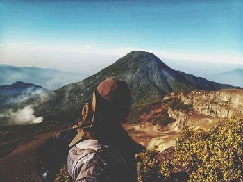 Midsection of man with mountain range against sky