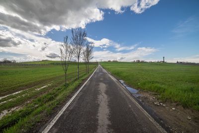 Road amidst field against sky