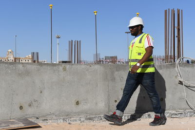 Man holding blueprints while walking at construction site