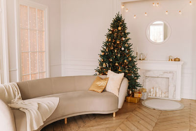 Bright decorated christmas interior of a living room with a sofa and a christmas tree in a  house
